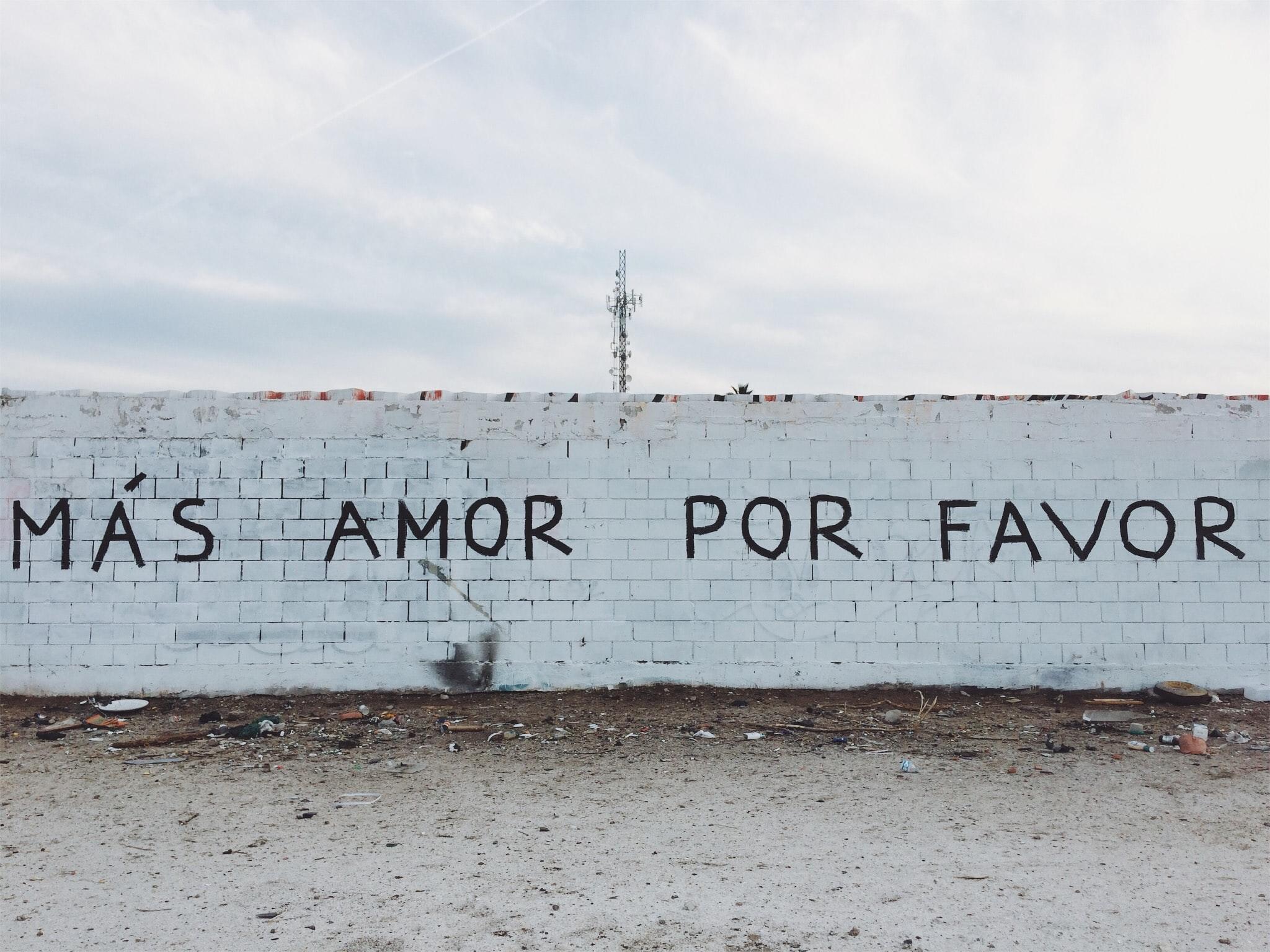 画在墙上的西班牙语句子，意思是“请给我更多爱”。